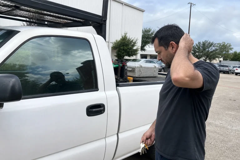 Man holding keys beside a white pickup truck.